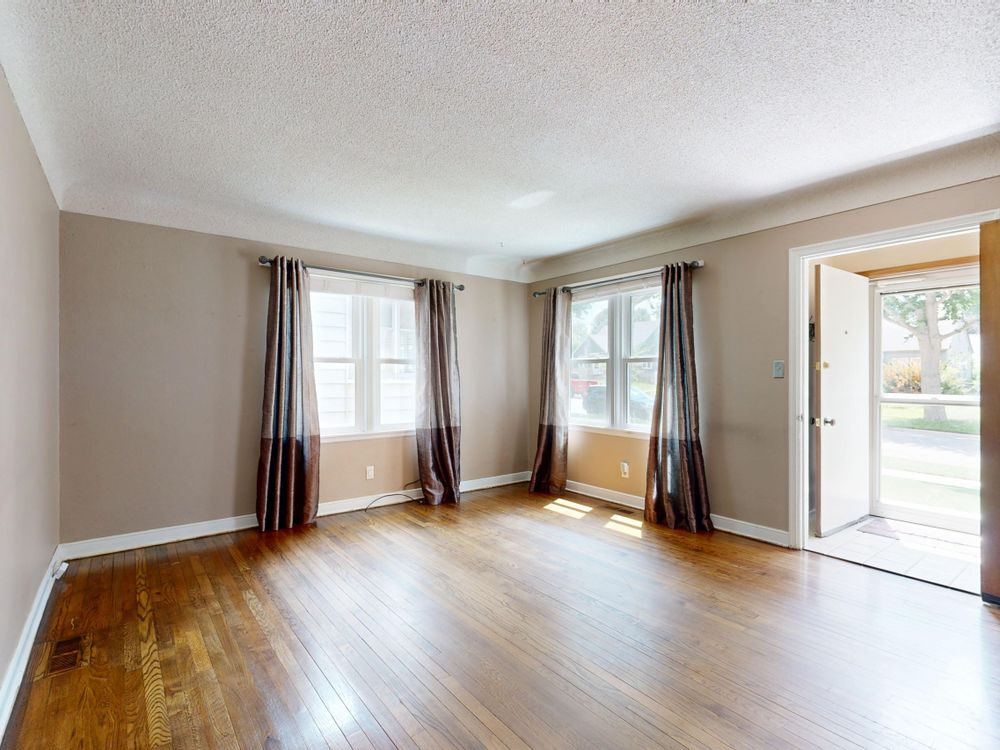An empty front room with a narrow-strip oak floor in a North End Halifax house.