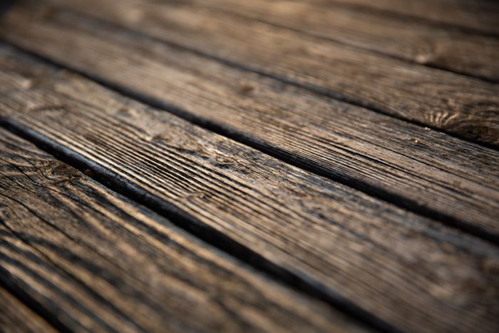 Close detail of grey, weathered floorboards with open gaps between them.
