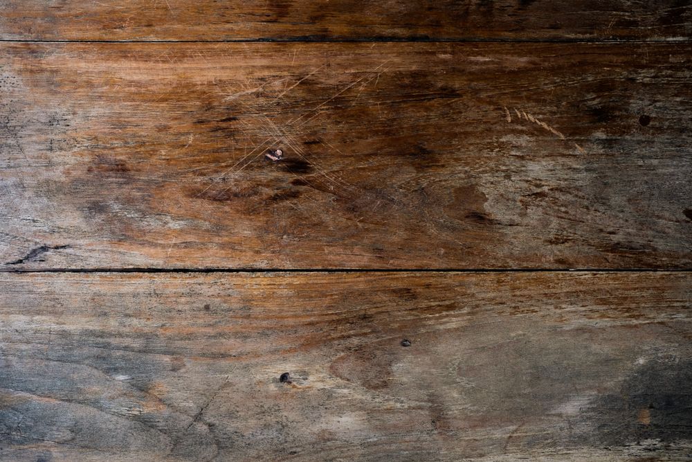 Worn floorboards with scratches and a finish that has gone through to the wood.
