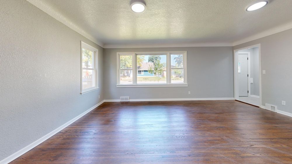 An empty room with a freshly refinished dark hardwood floor in a Dartmouth home.